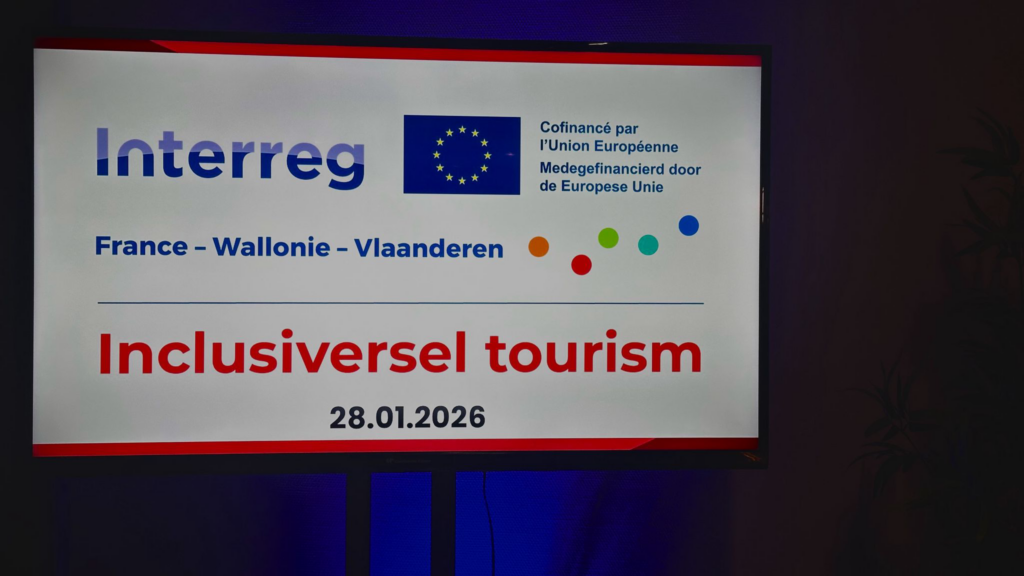 Photo d’une affiche blanche affichant les informations du projet Inclusiversel tourism. En haut, on voit les logos d’Interreg et de l’Union Européenne, suivis de la mention 'France - Wallonie - Vlaanderen'. Le titre 'Inclusiversel tourism' est écrit en rouge, avec la date '28.01.2026' en dessous. L’affiche est encadrée par une bordure rouge.