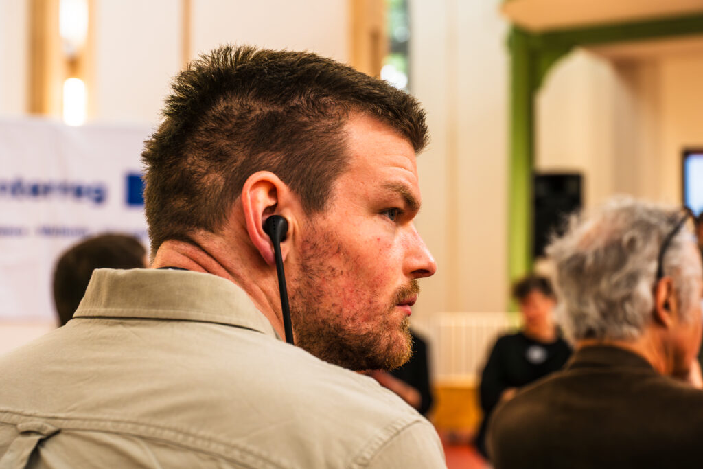 Gros plan de profil d'un participant portant des écouteurs de traduction simultanée.