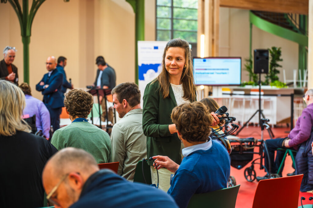 Une participante micro en main posant une question durant la conférence de lancement.