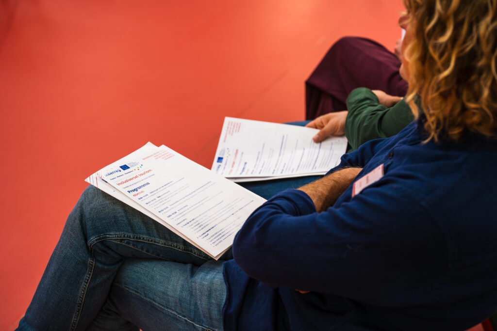 Gros plan sur les feuilles de programme du projet Interreg tenues par un participant.